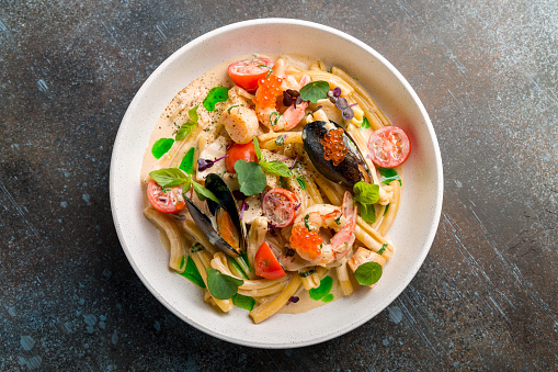Pasta with seafood, mussels,scallops, shrimps,red caviar and tomatoes on creamy sauce top view