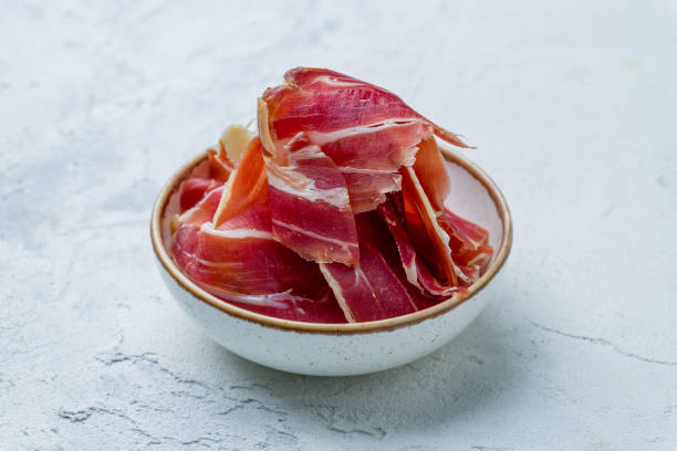 istock Spanish Jamon (Hamon), parma ham sliced on plate on white concrete table 1415487687