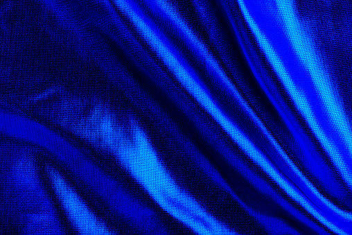 Piece of blue satin fabric as abstract background. Silky and shiny texture.