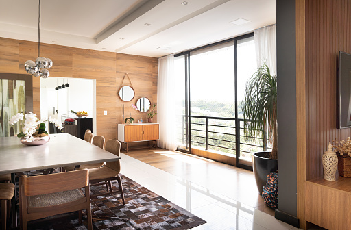 Interior of the bright dining room of a luxury home with sliding windows with a view in summer