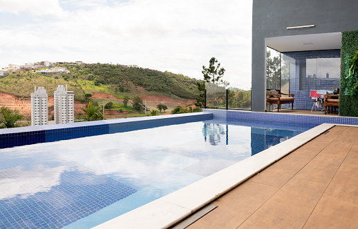 Swimming pool reflecting the sky in the back yard of a home with a scenic view in the summertime