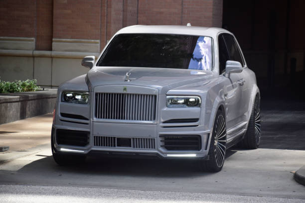 Portrait of a Rolls-Royce Cullinan Wide Body SUV by Mansory A white custom-built Rolls-Royce Cullinan by Mansory exits hotel driveway in downtown Houston, TX rolls royce stock pictures, royalty-free photos & images