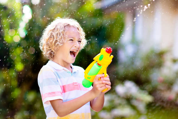 dzieci z bronią wodna w ogrodzie. zabawa na świeżym powietrzu. - toy gun zdjęcia i obrazy z banku zdjęć