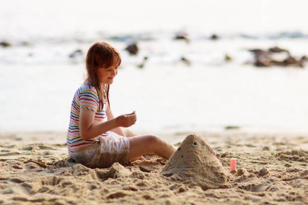 Little girl playing on tropical beach. Children play at sea shore. Water and sand fun. Summer vacation. Travel with kids. Ocean holiday with child. Sunset walk at the beach.