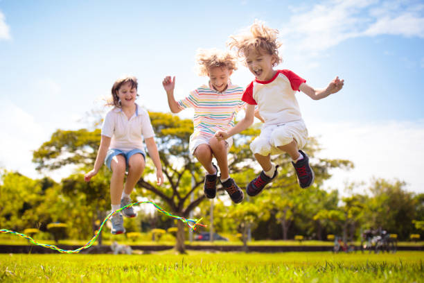 les enfants heureux jouent à l’extérieur. enfants à la corde à sauter. - sautiller photos et images de collection