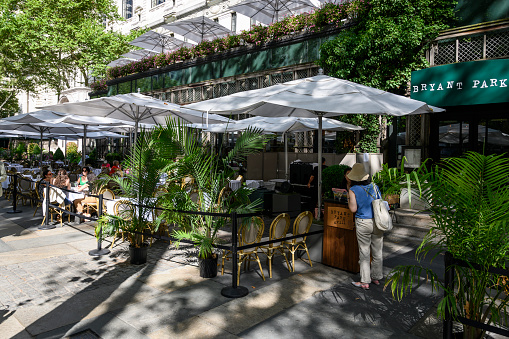 New York, New York, USA - August 1, 2022: Bryant Park. Cafe with outdoor seating. People can be seen.