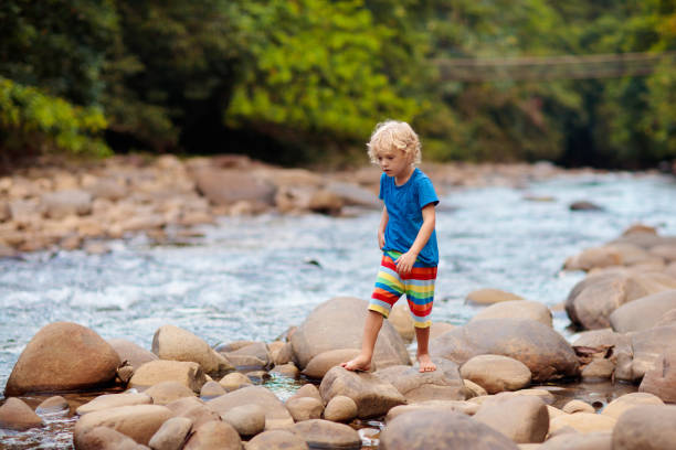 istock Child hiking in mountains. Kids at river shore. 1415496046