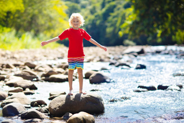 istock Child hiking in mountains. Kids at river shore. 1415496818