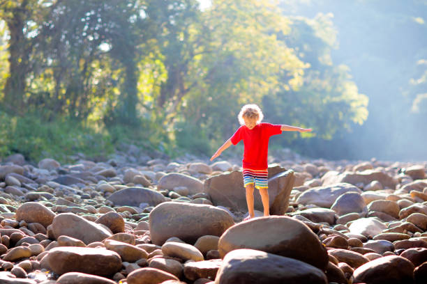 istock Child hiking in mountains. Kids at river shore. 1415496865