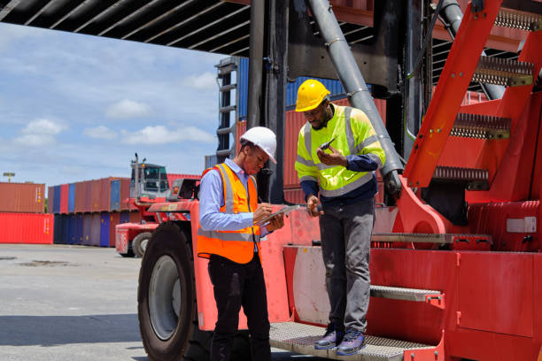 Two Black male worker works at a logistics terminal with stacks of containers. stock photo