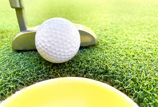 Golf ball with putter near cup stock photo