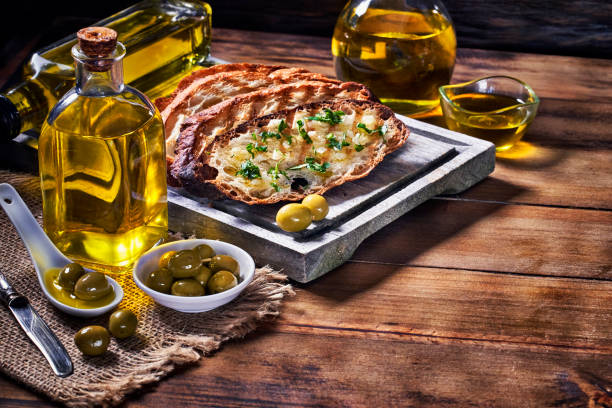snack or appetizer of garlic basil and olive oil bruschetta on table in a rustic kitchen with copy space - bruschetta cutting board italy olive oil imagens e fotografias de stock