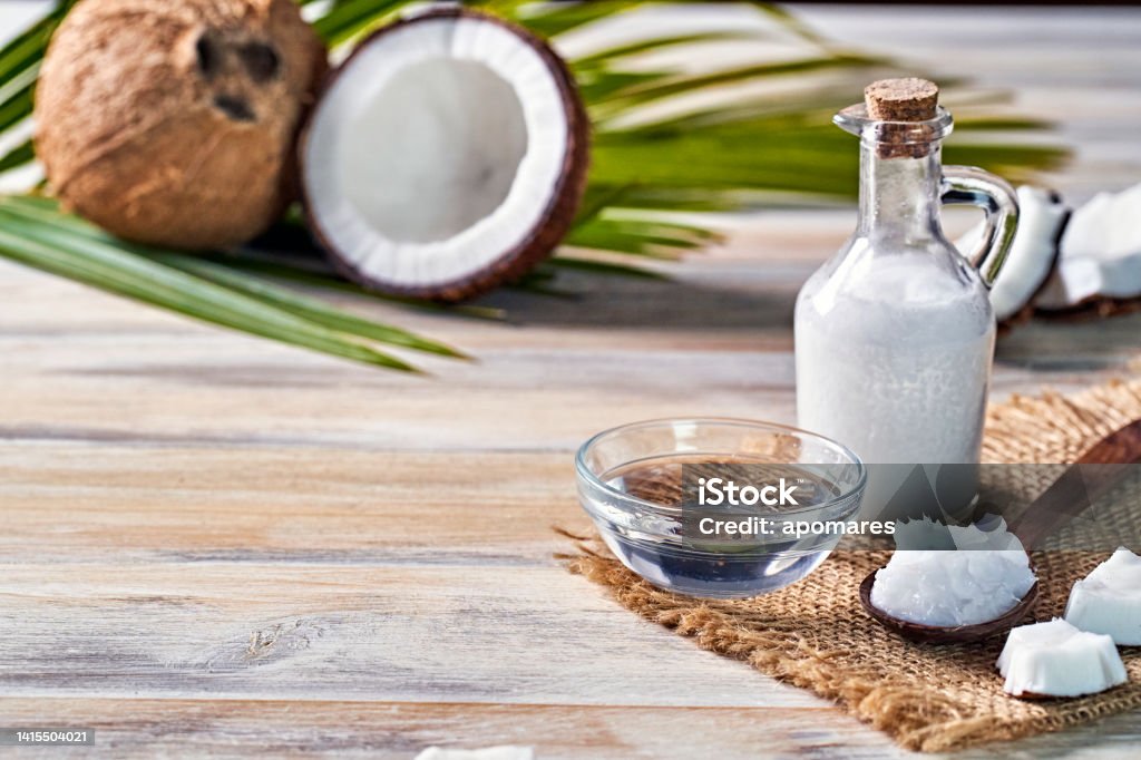 Glass bottle of coconut oil and fresh coconut fruit on wooden rustic white background Glass bottle of coconut oil and fresh coconut fruit on wooden rustic white background, alternative therapy medicine concept Alternative Therapy Stock Photo