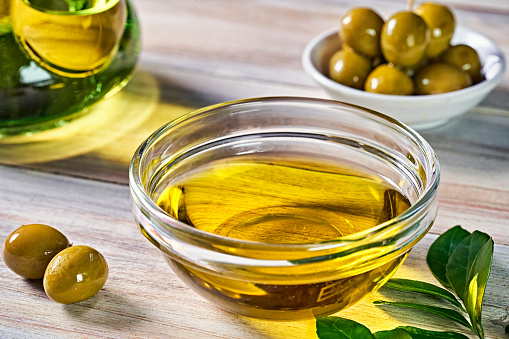bottle with olive oil and fresh olive fruits on blue sky background