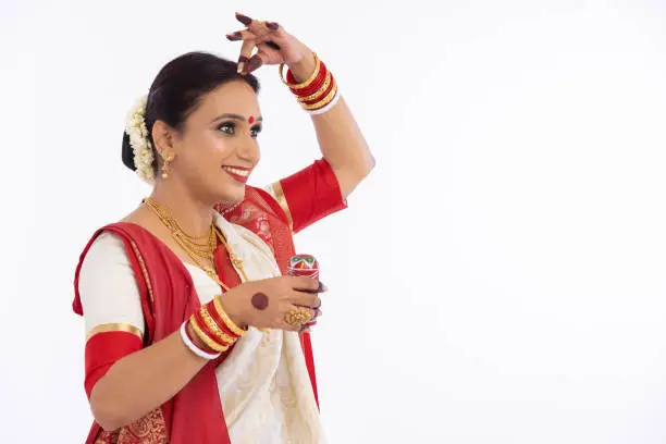 Woman putting sindoor on forehead over white background