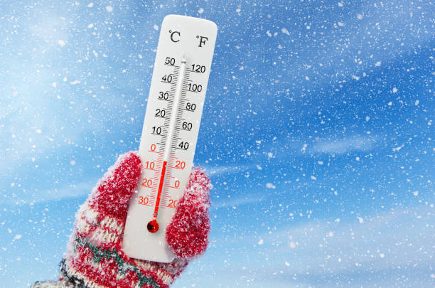 White celsius and fahrenheit scale thermometer in hand. Ambient temperature minus 4 degrees celsius stock photo
