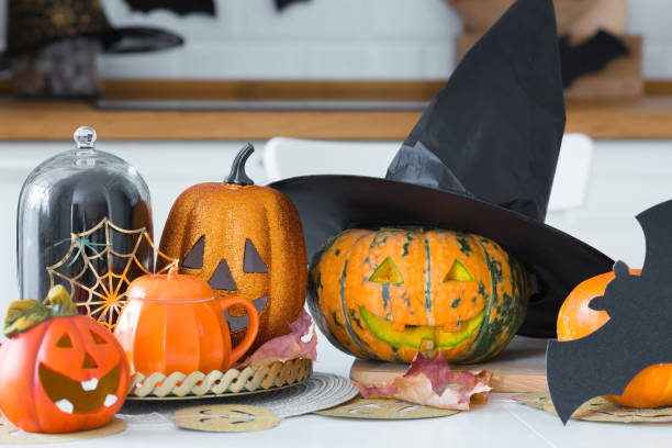 istock Happy Halloween! Pumpkin Jack on the table. Lantern with a carved smile and different attributes of the holiday on a light background in the interior. For family holidays at home. Copyspace. 1415525089
