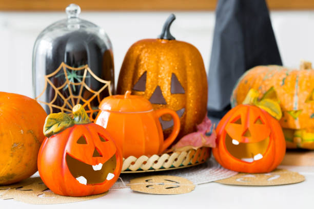 istock Happy Halloween! Pumpkin Jack on the table. Lantern with a carved smile and different attributes of the holiday on a light background in the interior. For family holidays at home. Copyspace. 1415525090