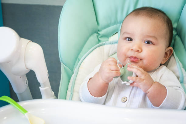 istock A happy and contented baby eats banana puree from a nipple. Introduction of complementary foods, healthy baby food, feeding the baby at the table 1415527335
