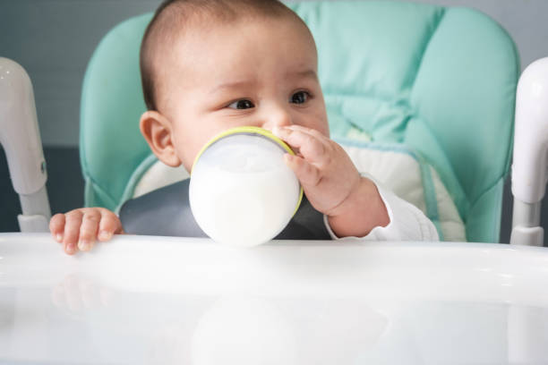 istock The baby eats from a bottle at the feeding table. Introduction of complementary foods, child care 1415527353