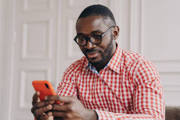 istock Cheerful millennial biracial man using smartphone, sitting at desk 1415531882