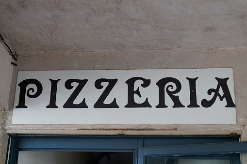Pizzeria text sign from Italy on facade street outside entrance door restaurant italian
