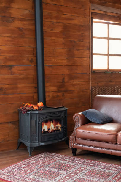 Classic black cast iron fire place with wood burning inside of it. Fragment of the interior of a country house. The iron furnace is heated. Wood burning stove, traditional heating system. stock photo