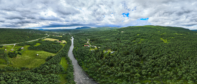 A raging river runs through deep green forest landscape. Seen from above in the village of Bruksvallarna, Harjedalen, Sweden.