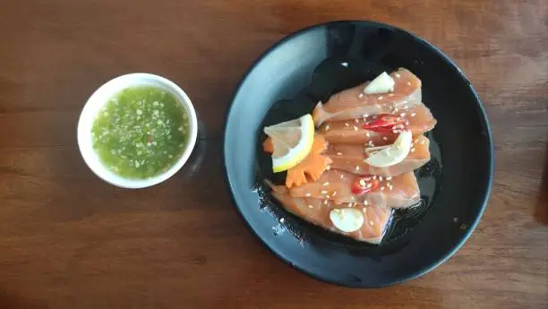 Pickled salmon with Thai style spicy sauce on wooden table
