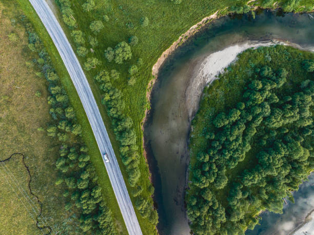 istock Car driving on road surrounded by river and forest 1415537932