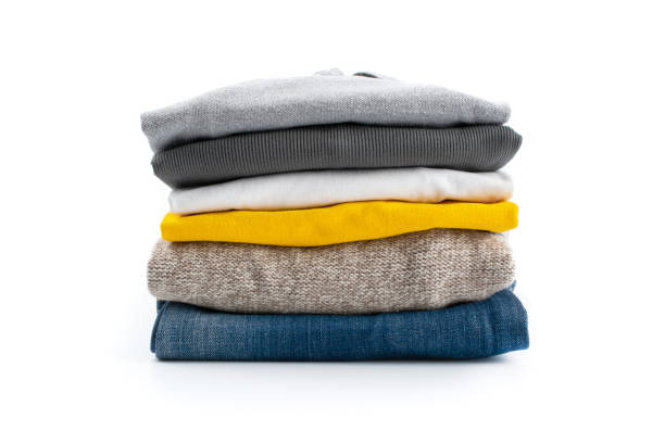Vertical shot of a stack of folded clothes. Vertical shot of a stack of folded clothes. Isolated on a white background. folded stock pictures, royalty-free photos & images