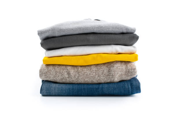 Vertical shot of a stack of folded clothes. Vertical shot of a stack of folded clothes. Isolated on a white background. garment stock pictures, royalty-free photos & images