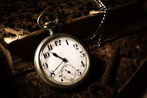 istock Open pocket watch and a stack of books. 1415540272