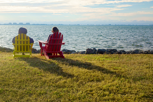 Rear view of two women sitting on Adirondack Chairs and watching seascape in Sarasota, Florida