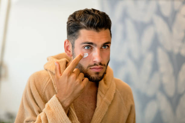 istock Young man applying cream on cheek 1415542677