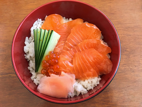 Close-up Shot of Salmon Sashimi Rice Bowl with slice of cucumber, pickled ginger and caviar