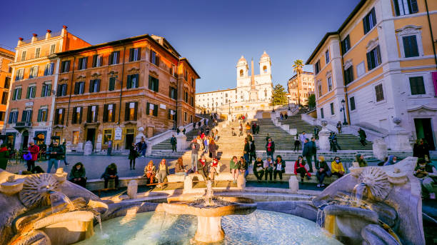 A warm sunset light illuminates the Barcaccia Fountain and Piazza di Spagna in the Baroque heart of Rome stock photo