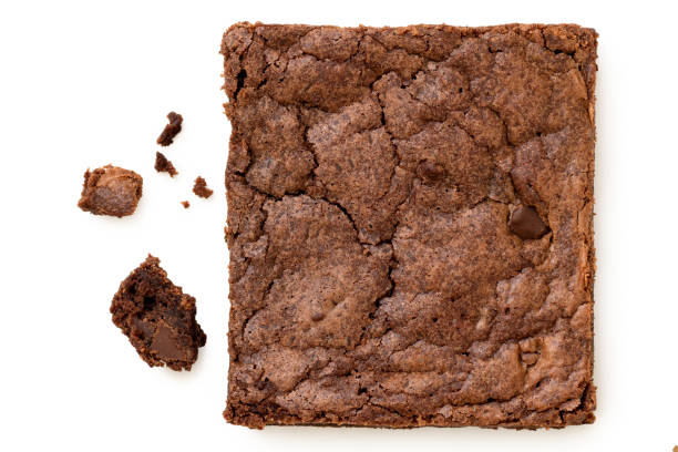 istock Chocolate brownie with chocolate chips next to crumbs isolated on white from above. 1415546565