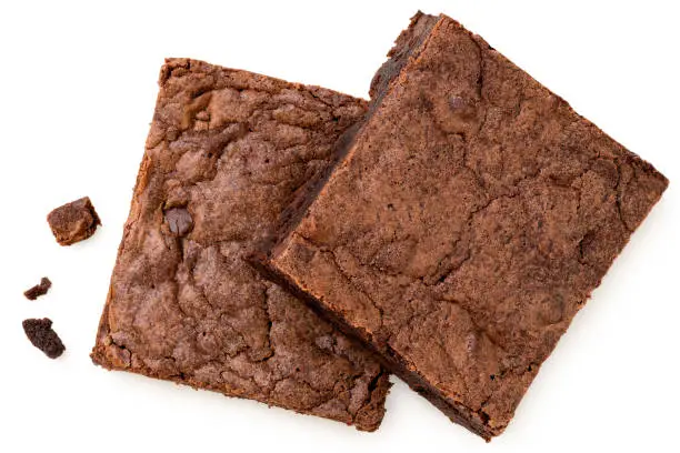 Two chocolate brownies with chocolate chips next to crumbs isolated on white. Top view.