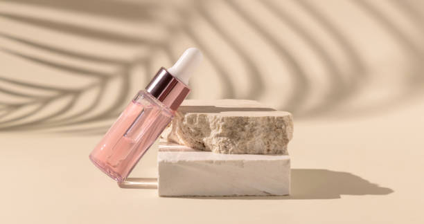 istock Dropper Bottle on travertine stone and palm leaf shadow on light yellow 1415551844
