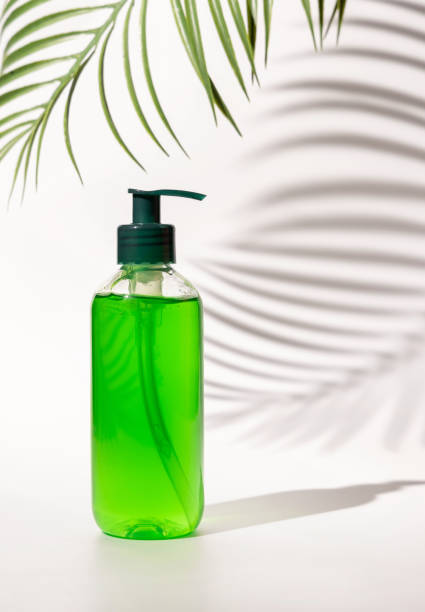 istock Cosmetic pump dispenser bottle filled with green liquid on white, Palm leaf hard shadows 1415551884