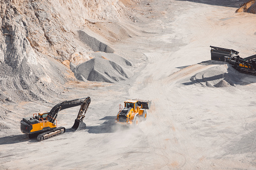 Female architect explaining plan to quarry worker at construction site against clear sky