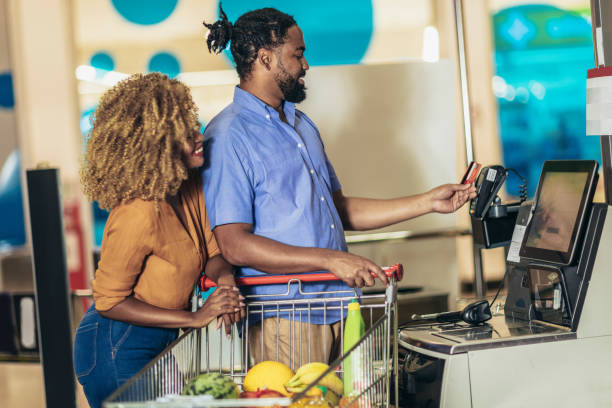 African American Couple with bank card buying food at grocery store or supermarket African American Couple with bank card buying food at grocery store or supermarket self-checkout self checkout stock pictures, royalty-free photos & images