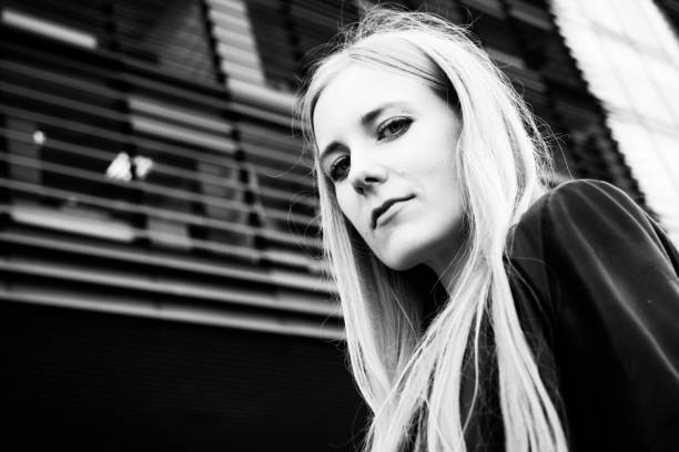 Black and white portrait of a beautiful young cheerful blonde woman lying on bed.