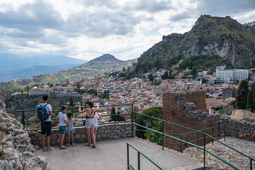 Taormina, Sicily, Italy - July 10, 2022: Tourists watch the panorama of Taormina from the observation deck