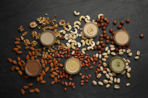 istock Different types of delicious nut butters and ingredients on black table, flat lay 1415559656