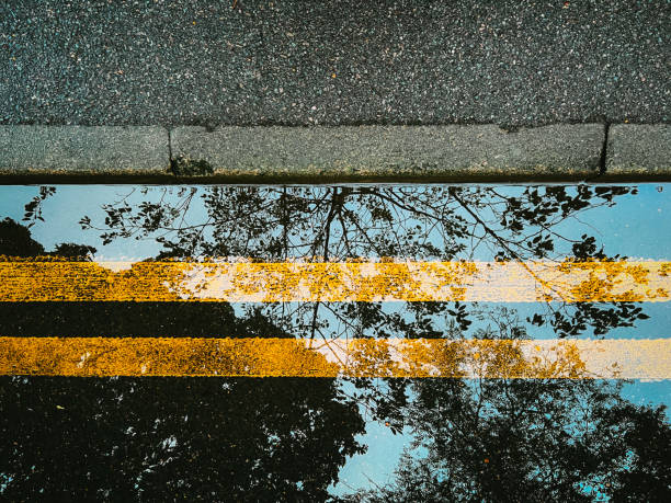 Abstract reflection of double yellow lines on road beneath flood water stock photo