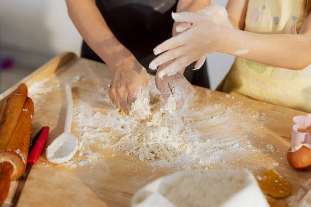 zbliżenie ujęcia młodych dziewcząt rękami wyrabiającymi ciasto przygotowujące domową pizzę ze składników mąka z jaj i sprzęt kuchenny łyżka i nóż - equipmet zdjęcia i obrazy z banku zdjęć