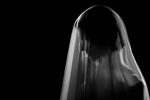 woman under white veil posing sensually on black background with copy space, profile side view monochrome