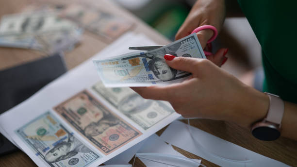 istock Female hand cuts counterfeit money American dollars 1415564705